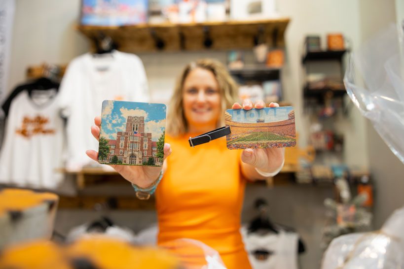 Alumna Janna Abraham holds up a coaster and a keychain in her booth selling Tennessee items