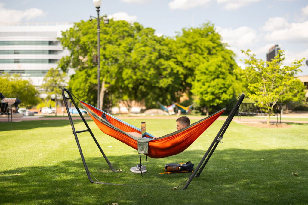 A student works on a laptop while in a hammock in Circle Park.